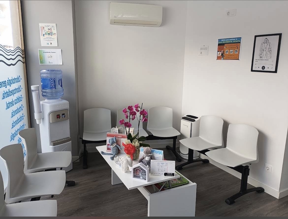 Sala de espera luminosa y minimalista con sillas blancas y orquídeas